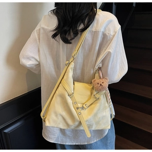 Detail of yellow leather tote bag with brown plush bear charm and fashion text