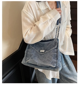 Blue denim crossbody bag featuring a woven chain strap and vintage silver metal turn lock