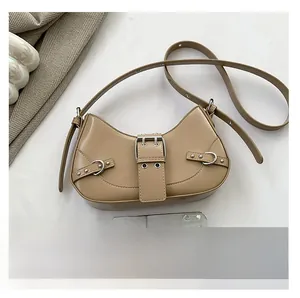 Detail view of khaki crescent shoulder bag with metallic eyelets and decorative buckles