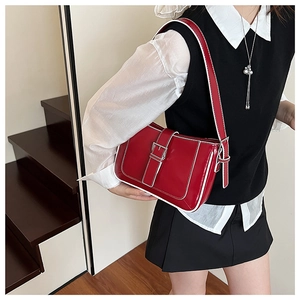 Detail of red glossy shoulder bag featuring white contrast stitching and silver buckle