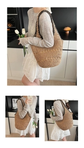 Detail of hand-woven straw tote bag with black contrast straps and large capacity design