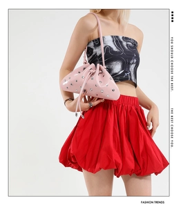 Detail of pink patent leather bucket bag with silver studs and drawstring closure