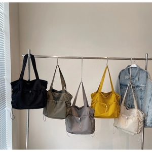 Row of large capacity nylon tote bags in five colors with drawstring and front pockets