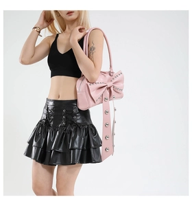 Detailed shot of pink faux leather handbag featuring silver studs and oversized bow decoration