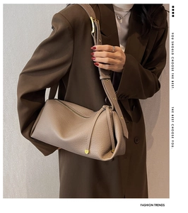 Detail of taupe pebbled leather texture on minimalist crossbody bag with gold hardware