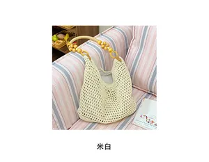 Detail of beige straw bag with round wooden handles and beaded accents on a sofa