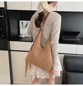 Detail of bohemian brown woven tote bag with long side fringes and leather strap