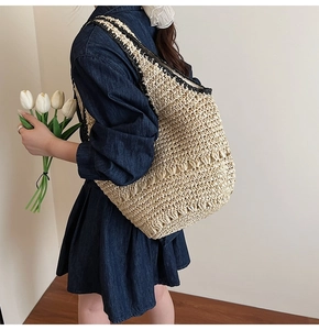 Detail of woven straw shoulder bag with black trim and hollow knit texture on model