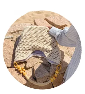 Detail of hand-woven straw beach bag featuring large wooden beads on the handle