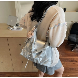 Detail showing metallic silver tote bag with plush bear charm and fashion text