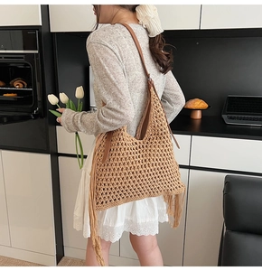 Detail of handwoven crochet tote bag featuring stylish long tassels and brown leather straps