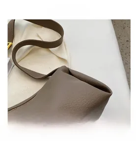 Macro detail of lychee pattern leather and gold metal hardware on retro pillow bag