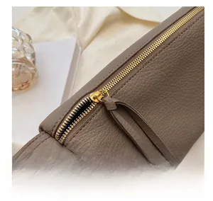 Macro shot of gold metal zipper and pebble grain leather on a brownish gray handbag