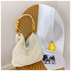Detail of crochet tote bag with round wooden bead handles and cream mesh woven texture