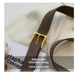 Close-up of brown litchi grain leather shoulder strap with golden buckle detail