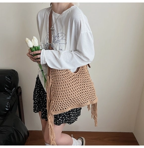 Detail of beige woven tote bag with long tassels and brown leather adjustable strap