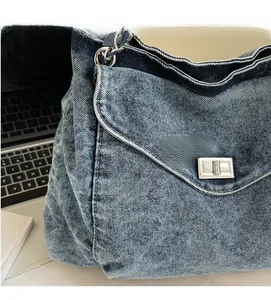 Detail of blue washed denim tote bag showing metal twist lock and white stitching contrast