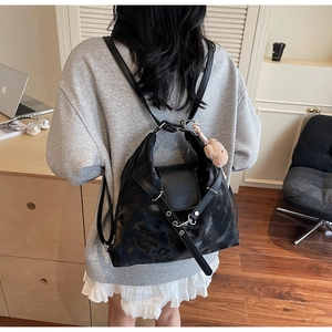 Detailansicht der schwarzen Tasche mit Marmortextur und braunem Plüschbär-Anhänger