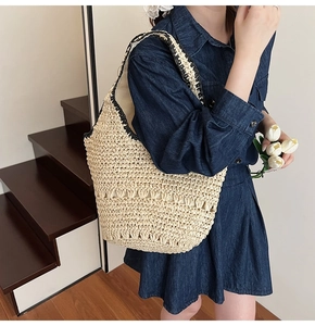 Close-up of straw woven tote bag featuring black contrast trim and hollow knit texture