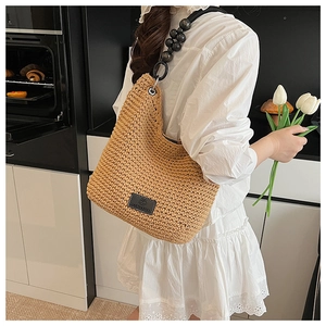 Detail of khaki woven bucket bag with elegant black beaded shoulder strap for women