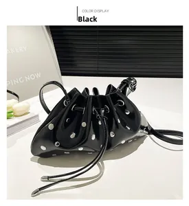 Detail of black drawstring bucket bag with silver rivet studs and patent leather finish