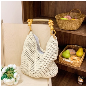 Detail of woven mesh tote with wooden bead handles and soft fabric inner lining