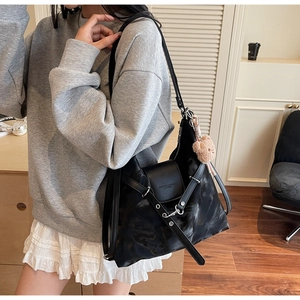 On-body shot of large marble-patterned tote bag with a cute plush bear charm