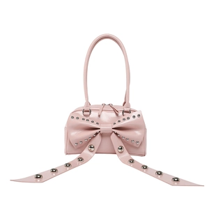 Pink patent leather shoulder bag with large bow and silver studs on white background