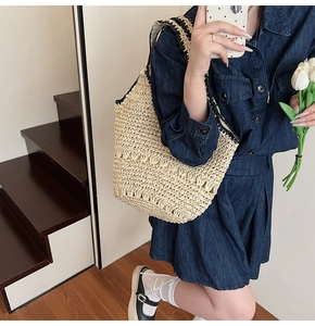 Detail of hollow woven straw shoulder bag with contrast knit strap and beach style texture