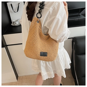 Detail of woven tote bag with unique black matte beaded shoulder strap and leather logo