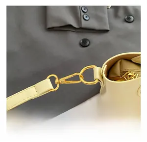 Detail van een hoogwaardige gouden karabijnsluiting op een beige lederen emmertas