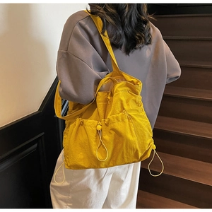 Detailed side view of bright yellow tote bag with drawstring pocket on a model