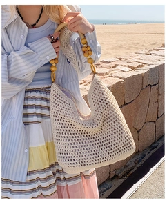 Detailed texture of hand-woven straw beach bag with decorative wooden bead handles