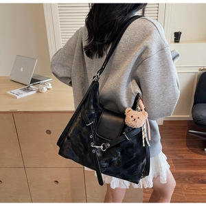 Close-up of black hobo bag with vintage texture and bear charm in lifestyle setting