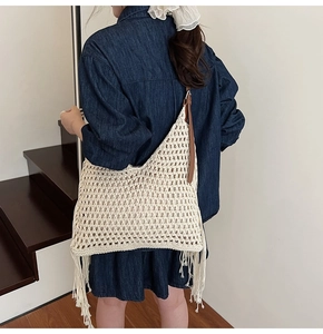 Detail of handmade woven tote bag with hollow mesh design and bohemian long tassels