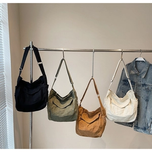 Detail view of large denim canvas crossbody bags in four colors with front flap pocket