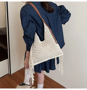 Detail of hand-woven crochet tote bag with long side tassels and brown leather straps