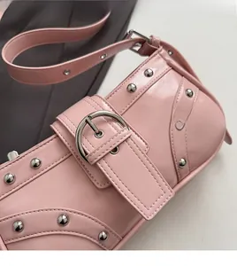 Détail du sac sous le bras en cuir verni rose avec rivets argentés et large boucle