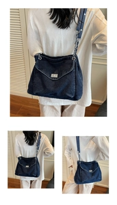 Detail of silver chain strap and metal lock on a navy blue denim commuter bag