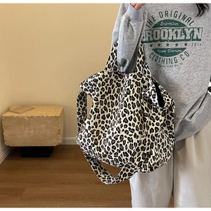 Detailed view of the large leopard print canvas tote bag worn by a model in a cozy room