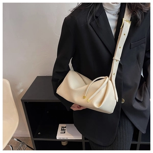 Close-up of cream lychee texture crossbody bag with unique pleated design on a black blazer