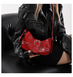 Close-up of vibrant red crescent shoulder bag with silver studs and leather buckles