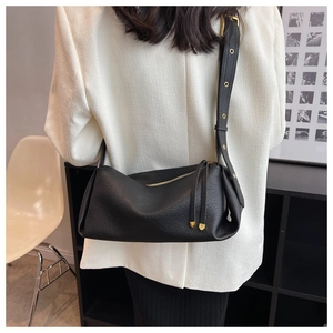 Close-up of black litchi leather bag featuring long tassels and gold metal eyelets