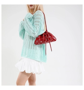 Detail of red glossy pleated dumpling bag featuring silver metallic stud accents