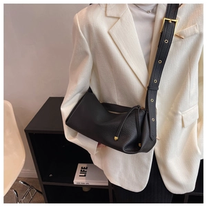 Close-up of black litchi grain leather bag with golden buckle and metallic eyelets
