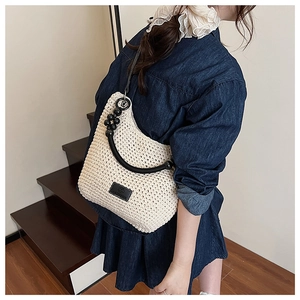 Detail of hand-woven cream hobo bag featuring black hardware and leather strap on model