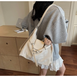 Detail of cream large capacity shoulder bag with metal chain and bear pendant accessory