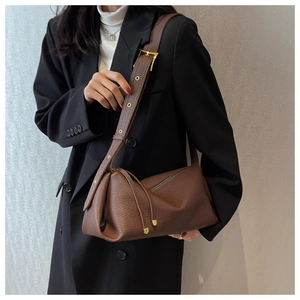 Detail of dark brown pebble leather shoulder bag with gold eyelets on wide strap