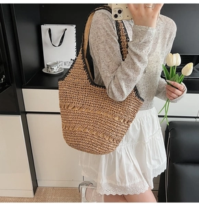 Detail showing the woven hollow stripe and black contrast handle on the straw tote bag