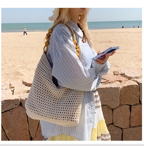 Detail of crochet straw beach bag featuring natural wooden bead shoulder straps